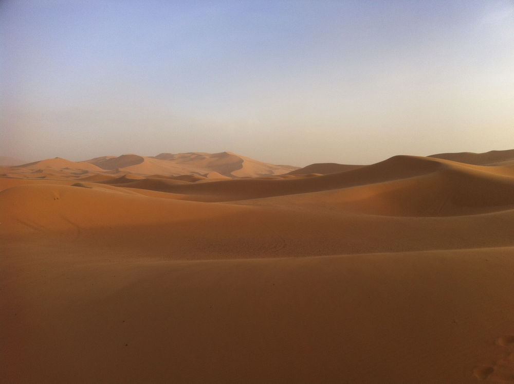 Weite Sanddünenlandschaft der Sahara in Marokko bei warmem Licht